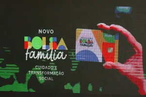Cartão do Novo Bolsa Família exibido em tela com mensagem sobre cuidado e transformação social