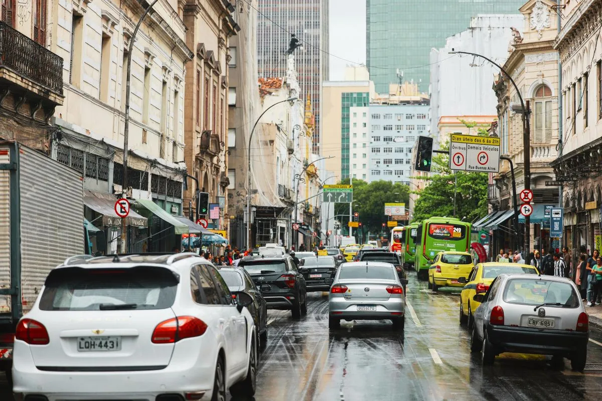 Trânsito intenso em avenida do centro de São Paulo com carros, ônibus e prédios históricos.