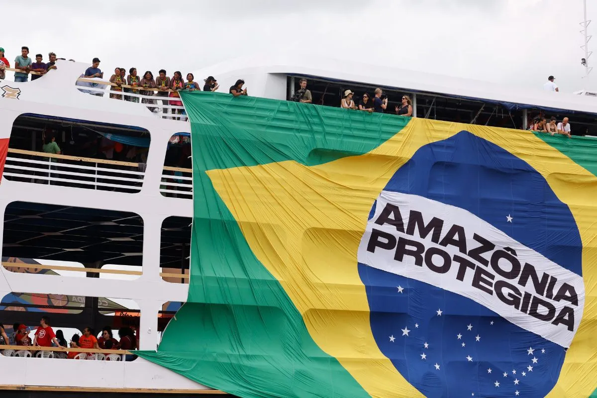Grande bandeira do Brasil com a frase Amazônia Protegida estendida em embarcação durante ato ambiental.