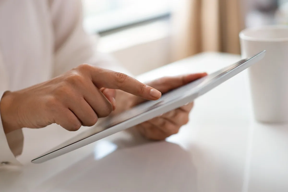 Pessoa utilizando tablet para ler notícias ou informações online em ambiente interno