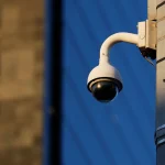 Câmera de vigilância instalada em poste realiza monitoramento de área urbana.