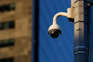 Câmera de vigilância instalada em poste realiza monitoramento de área urbana.
