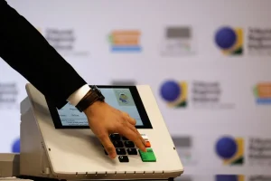 Mão de eleitor digitando números em urna eletrônica durante processo eleitoral