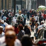 Grande fluxo de pessoas caminhando em rua movimentada de cidade do Brasil