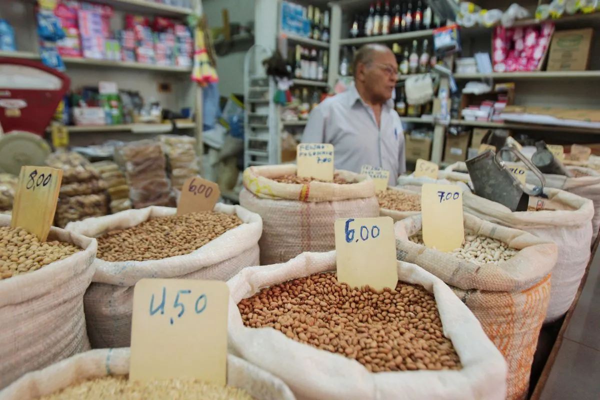 Sacos de feijão e grãos a granel com preços expostos em mercado popular brasileiro