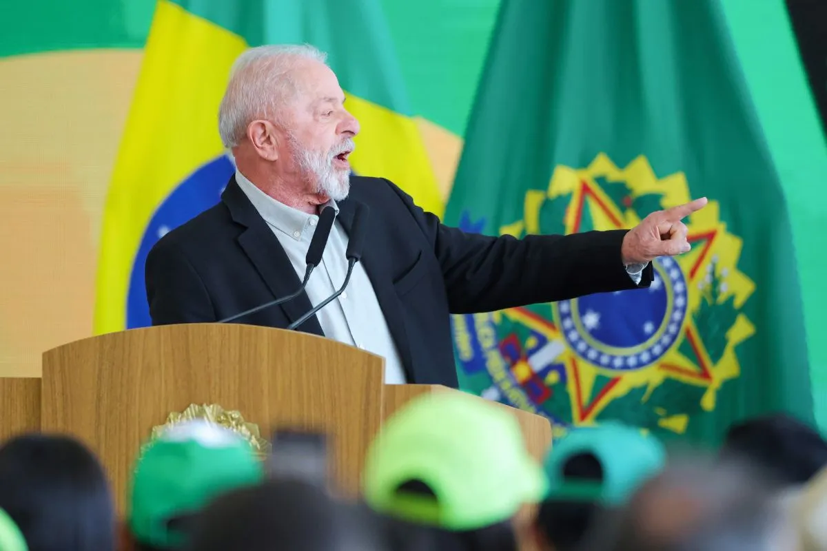 Presidente do Brasil discursando em púlpito com bandeiras oficiais ao fundo durante evento institucional