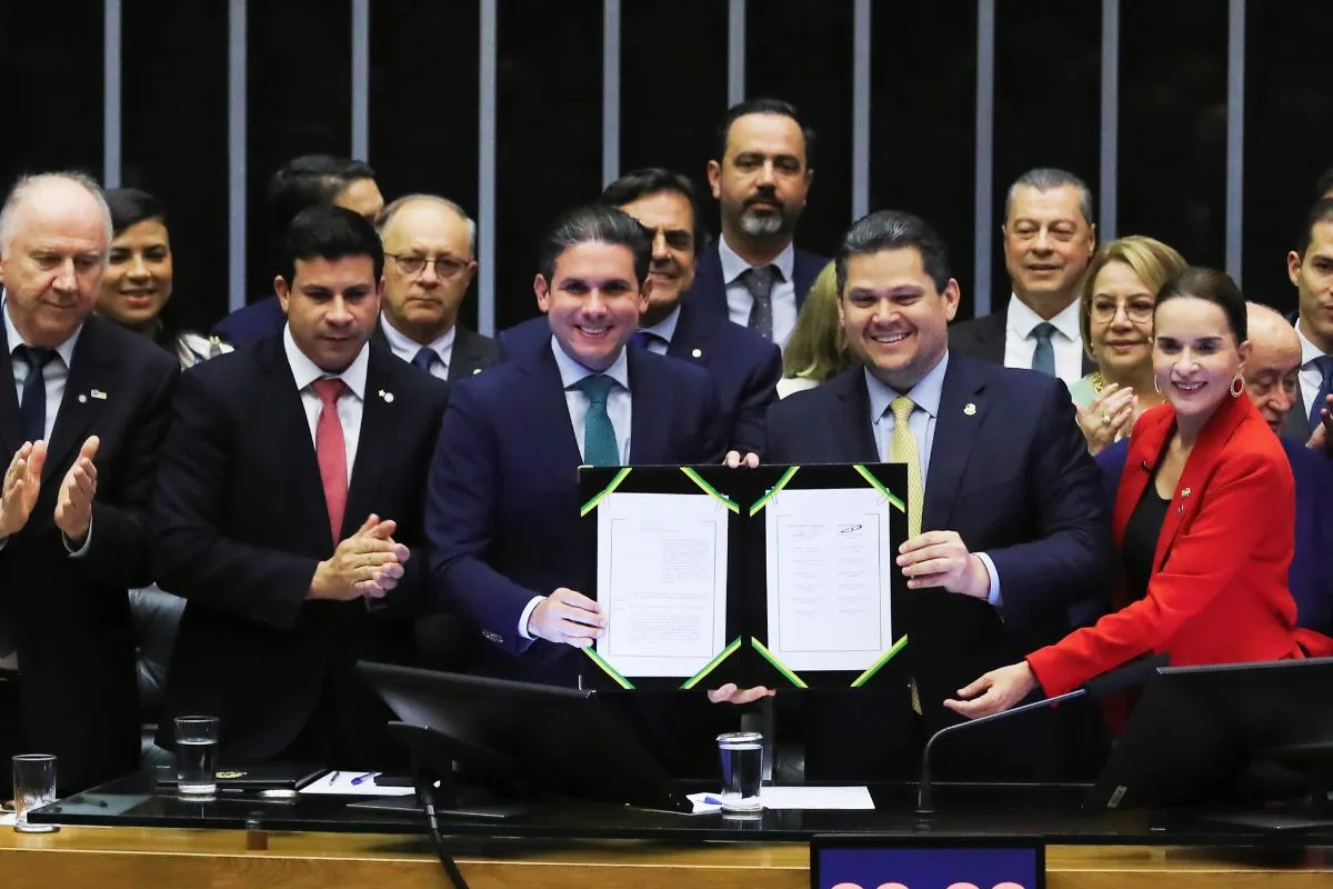 Parlamentares no plenário do Congresso Nacional exibem documento oficial após aprovação de projeto legislativo