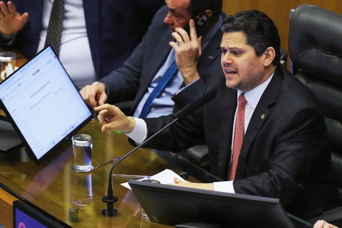 Parlamentar fala ao microfone durante sessão no Congresso Nacional, com computador e documentos sobre a bancada