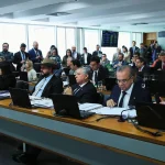 Deputados federais reunidos em sessão da Câmara dos Deputados, sentados no plenário com notebooks durante votação legislativa