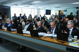 Deputados federais reunidos em sessão da Câmara dos Deputados, sentados no plenário com notebooks durante votação legislativa