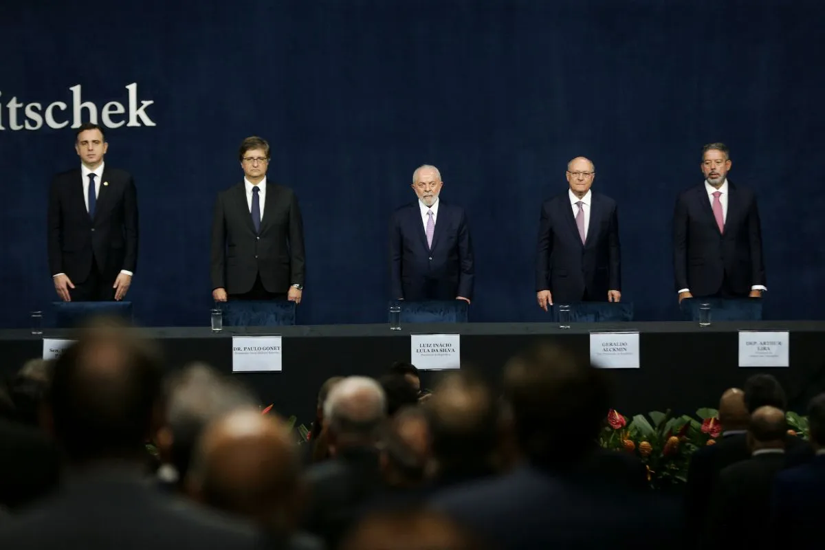 Autoridades brasileiras em pé durante cerimônia institucional, posicionadas atrás de mesa em auditório oficial.