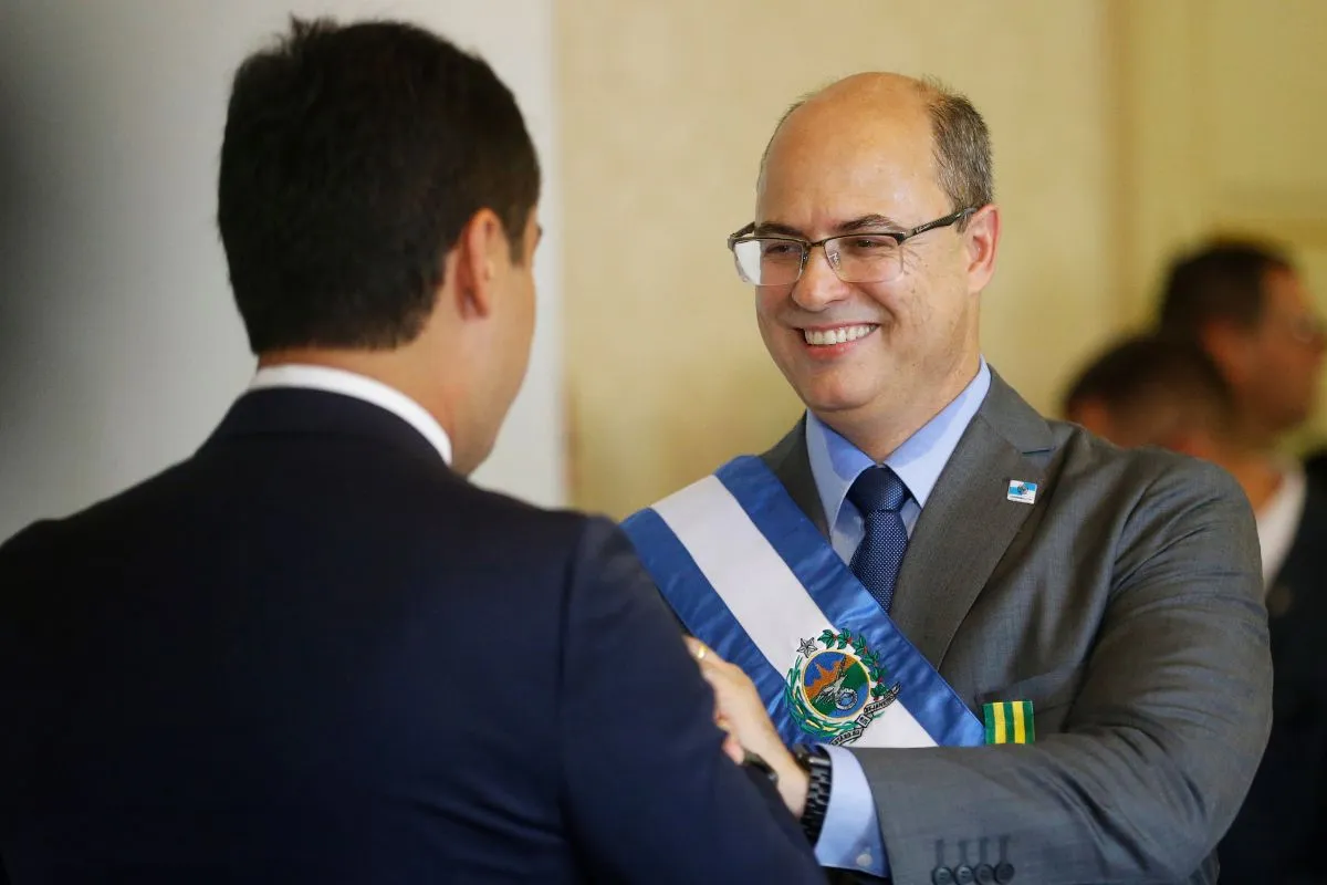 Autoridade pública recebe faixa oficial durante cerimônia de posse, em evento institucional com trajes formais.