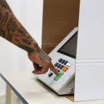 Roraima Mão de eleitor pressionando tecla de confirmação em urna eletrônica durante votação