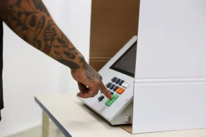Roraima Mão de eleitor pressionando tecla de confirmação em urna eletrônica durante votação