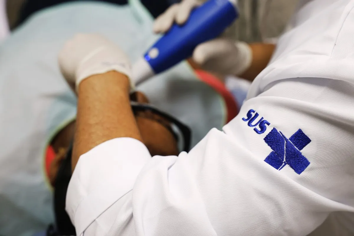Profissional de saúde realiza atendimento odontológico pelo SUS em paciente em clínica pública.