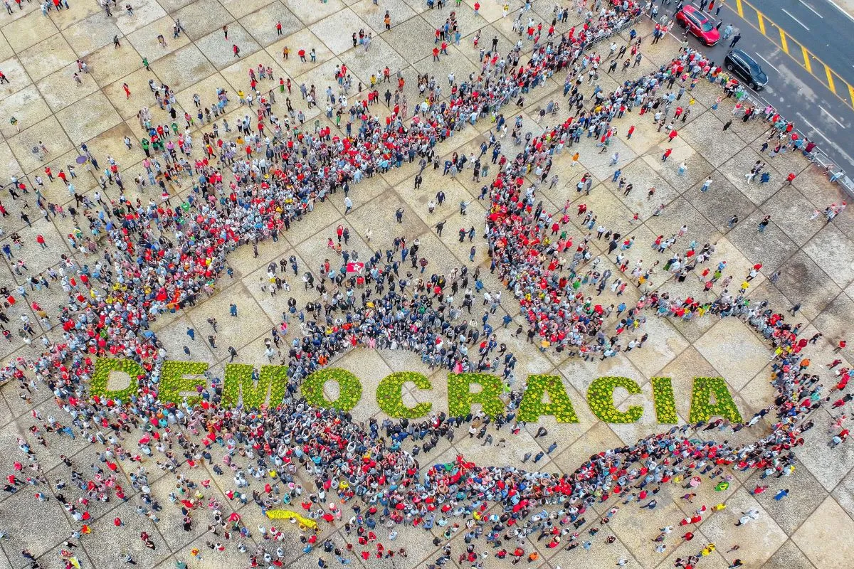 Vista aérea de multidão formando símbolo da democracia com a palavra democracia escrita no centro