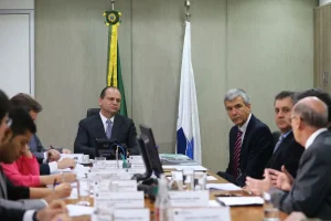 Autoridades reunidas em mesa de reunião institucional discutindo temas administrativos