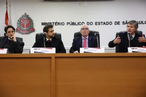Autoridades do Ministério Público sentadas à mesa durante coletiva oficial em sala institucional.