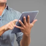 Homem utilizando tablet para acessar notícias do Brasil em ambiente neutro
