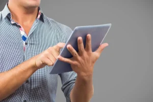 Homem utilizando tablet para acessar notícias do Brasil em ambiente neutro