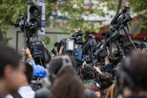 Jornalistas seguram microfones e celulares durante entrevista em cobertura de notícia política ao ar livre.