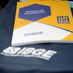 Manual do Recenseador do IBGE sobre colete oficial durante preparação para o Censo Demográfico.