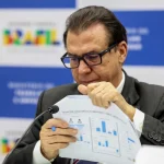 Autoridade do Ministério da Fazenda analisando relatório com gráficos de indicadores econômicos
