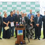 Grupo de parlamentares reunidos durante coletiva de imprensa na Câmara dos Deputados, em Brasília, com deputado discursando ao centro diante de microfones.