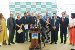 Grupo de parlamentares reunidos durante coletiva de imprensa na Câmara dos Deputados, em Brasília, com deputado discursando ao centro diante de microfones.