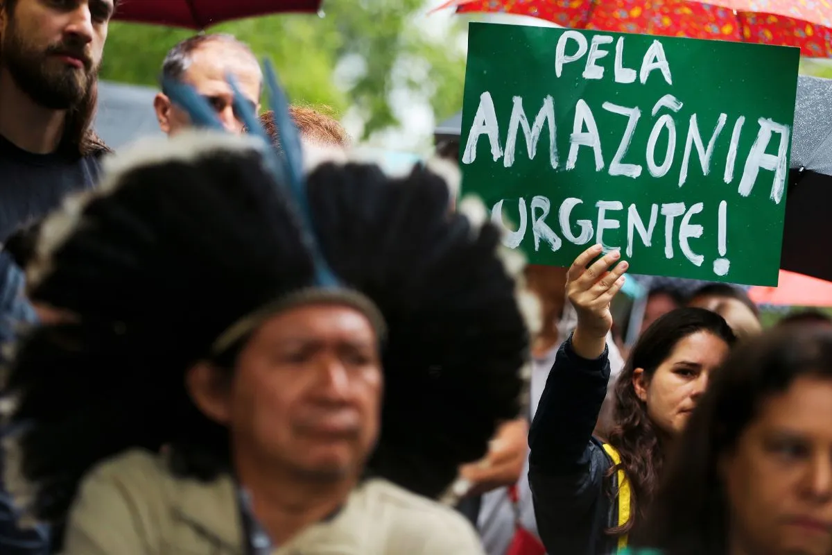 Manifestante segura cartaz com a frase Pela Amazônia Urgente durante protesto ambiental no Brasil.
