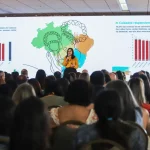 Palestrante apresenta dados sobre cuidados responsivos e desenvolvimento infantil para público em auditório lotado.