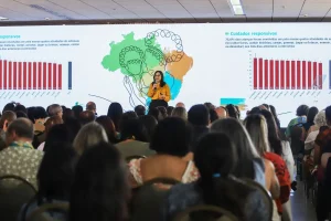 Palestrante apresenta dados sobre cuidados responsivos e desenvolvimento infantil para público em auditório lotado.