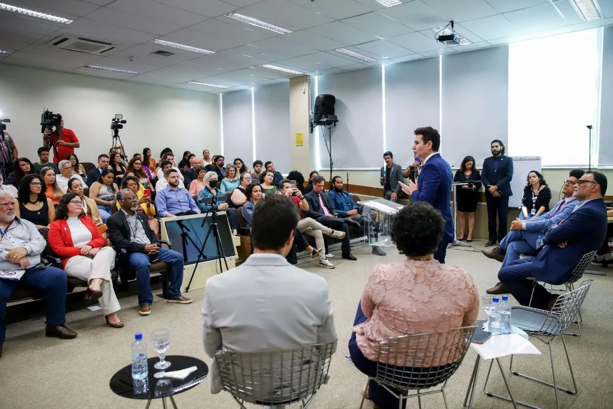 Autoridade apresenta propostas em audiência pública com plateia e representantes da sociedade civil em auditório.