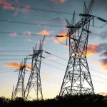 Torres de transmissão de energia elétrica ao entardecer representando infraestrutura do sistema elétrico brasileiro.