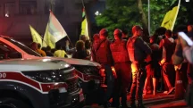 Policiais acompanham manifestação noturna com bandeiras e viatura ao fundo no Brasil violência