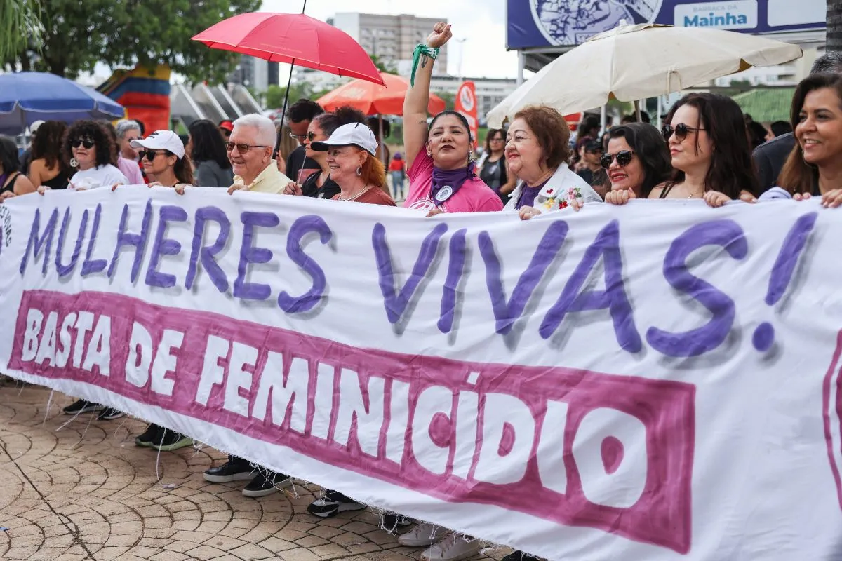 Mulheres seguram faixa com frase Mulheres Vivas Basta de Feminicídio durante manifestação