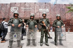 Militares do Exército Brasileiro com escudos de proteção em frente ao prédio da COP30 Brasil em Belém, durante evento da ONU sobre mudanças climáticas.