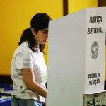 Mulher votando em cabine da Justiça Eleitoral durante processo de votação em eleições brasileiras.