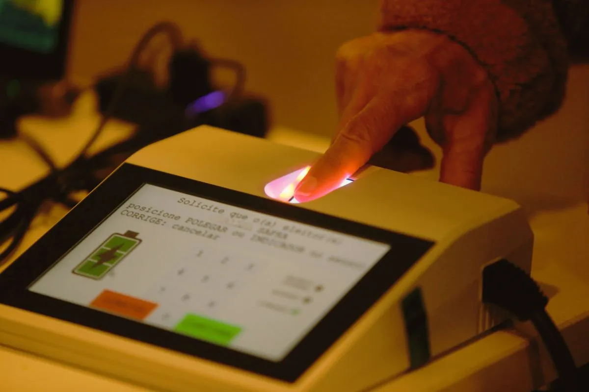 Eleitor utilizando leitor biométrico para identificação digital antes da votação nas eleições brasileiras.