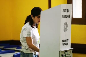 Mulher votando em cabine da Justiça Eleitoral durante processo de votação em eleições brasileiras.