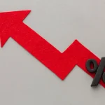 Seta vermelha em formato de gráfico ascendente com símbolo de porcentagem representando aumento da taxa de juros ou crescimento percentual.