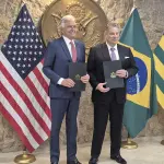 Foto do governador de Goiás, Ronaldo Caiado, e o Encarregado de Negócios na Embaixada dos Estados Unidos em Brasília, Gabriel Escobar. Ambos seguram na mão o memorando assinado por Caiado e Escobar, sobre a cooperação de minerais críticos (terras raras), no consulado dos EUA em São Paulo.