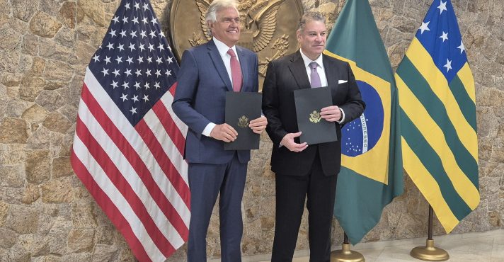 Foto do governador de Goiás, Ronaldo Caiado, e o Encarregado de Negócios na Embaixada dos Estados Unidos em Brasília, Gabriel Escobar. Ambos seguram na mão o memorando assinado por Caiado e Escobar, sobre a cooperação de minerais críticos (terras raras), no consulado dos EUA em São Paulo.