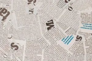 Recortes de jornais com a expressão fake news em destaque representando desinformação na mídia.