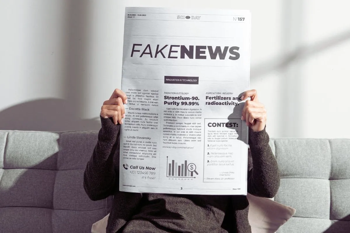 Pessoa segurando jornal com manchete fake news em destaque representando desinformação.