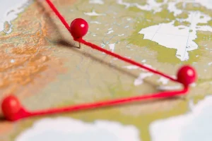Mapa com alfinetes vermelhos conectados por linha indicando rotas ou escalada de conflito geopolítico