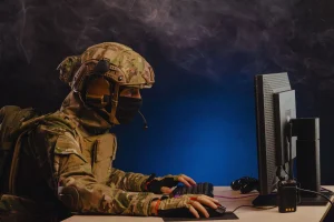 Soldado com equipamento tático utilizando computador em operação de guerra cibernética