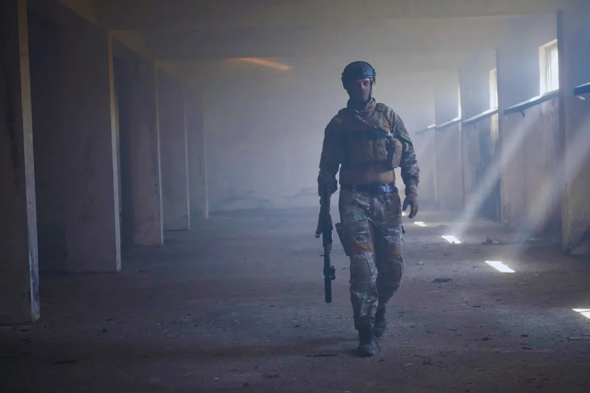 Soldado armado caminhando em prédio abandonado com iluminação dramática e fumaça