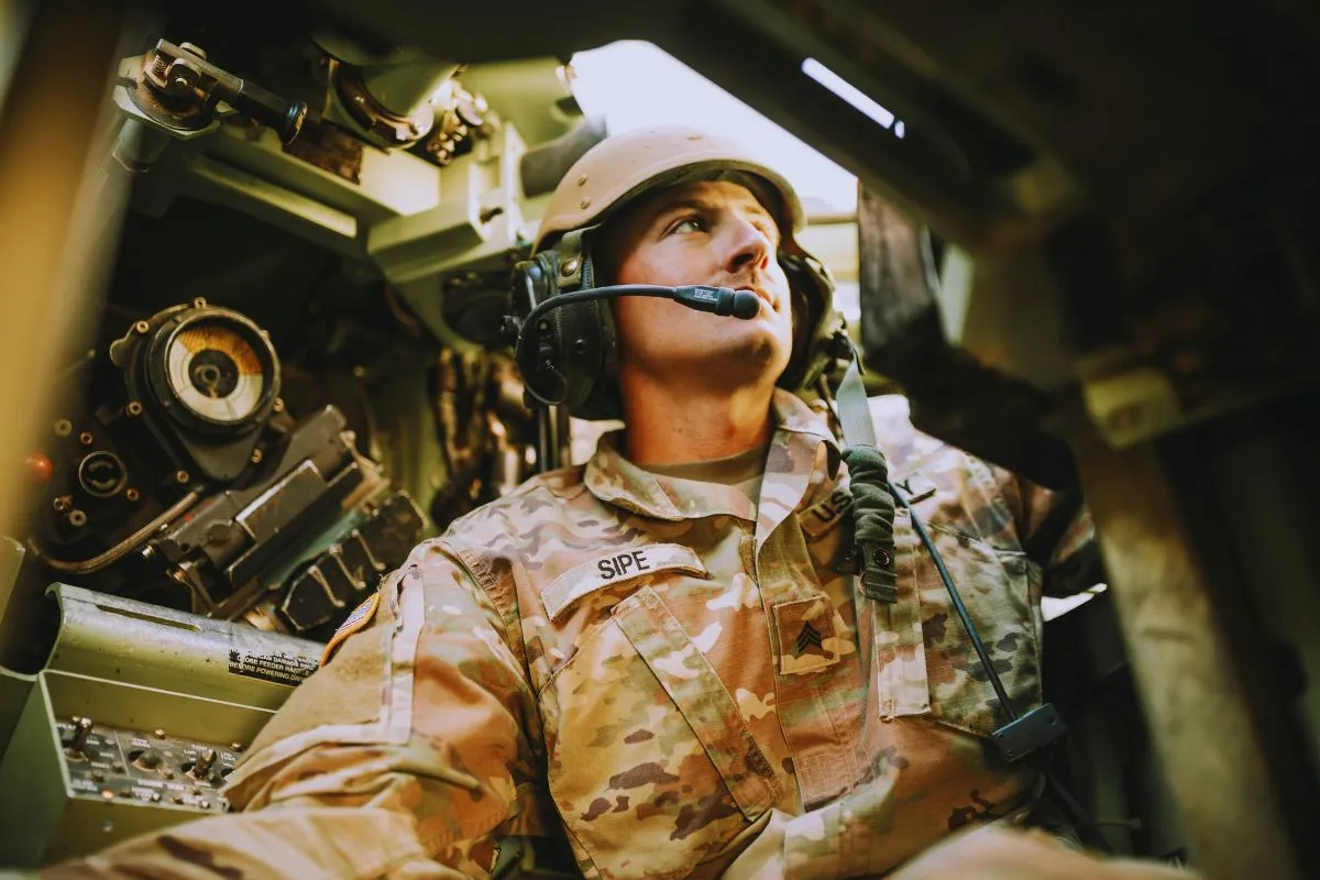 Militar dentro de veículo blindado usando headset e equipamentos de comunicação em operação