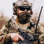 Soldado com uniforme camuflado e arma em posição de prontidão durante operação militar